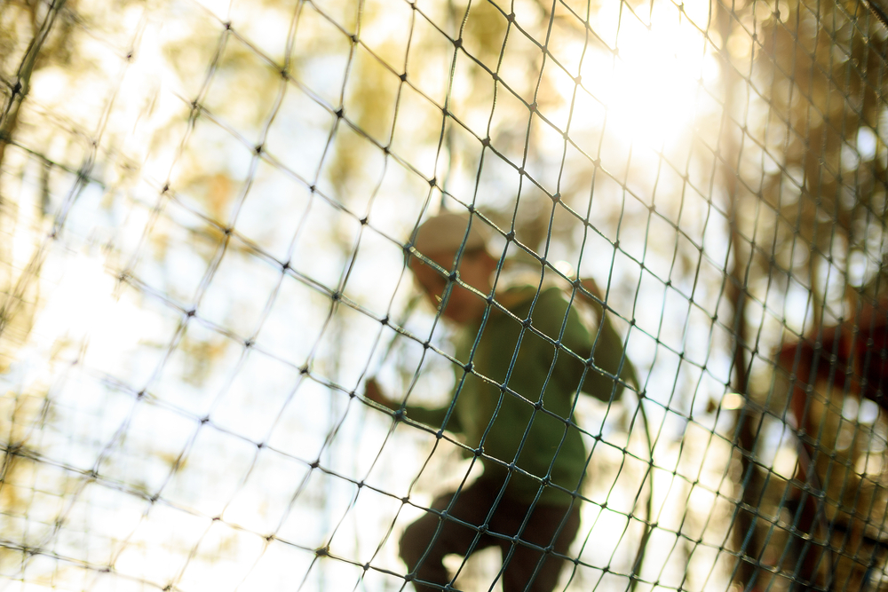 Boy plays in the playground shielded with a protective net.